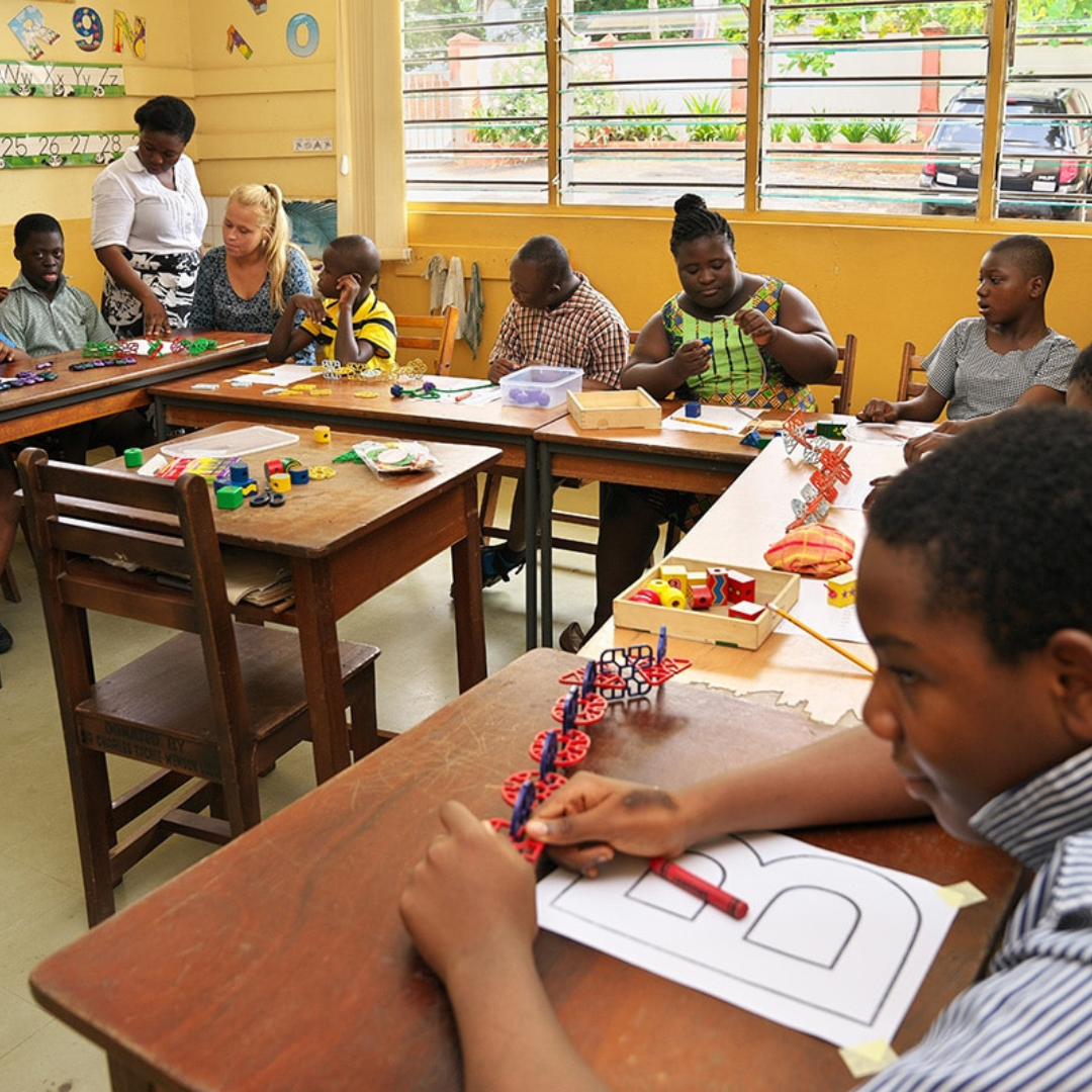 Several students learning colouring skills and blocks in a bright classroom.