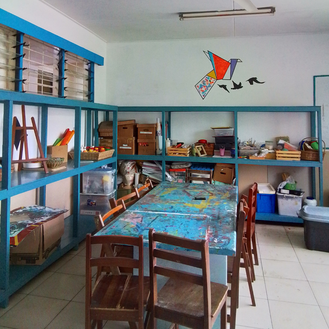 Bright blue shelves with art supplies and a colourful painted table.